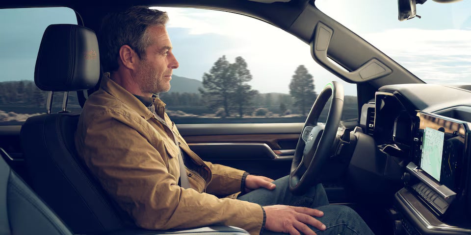 Driver comfortably seated in the 2025 Chevrolet Silverado, highlighting the spacious interior and driver-assist features.